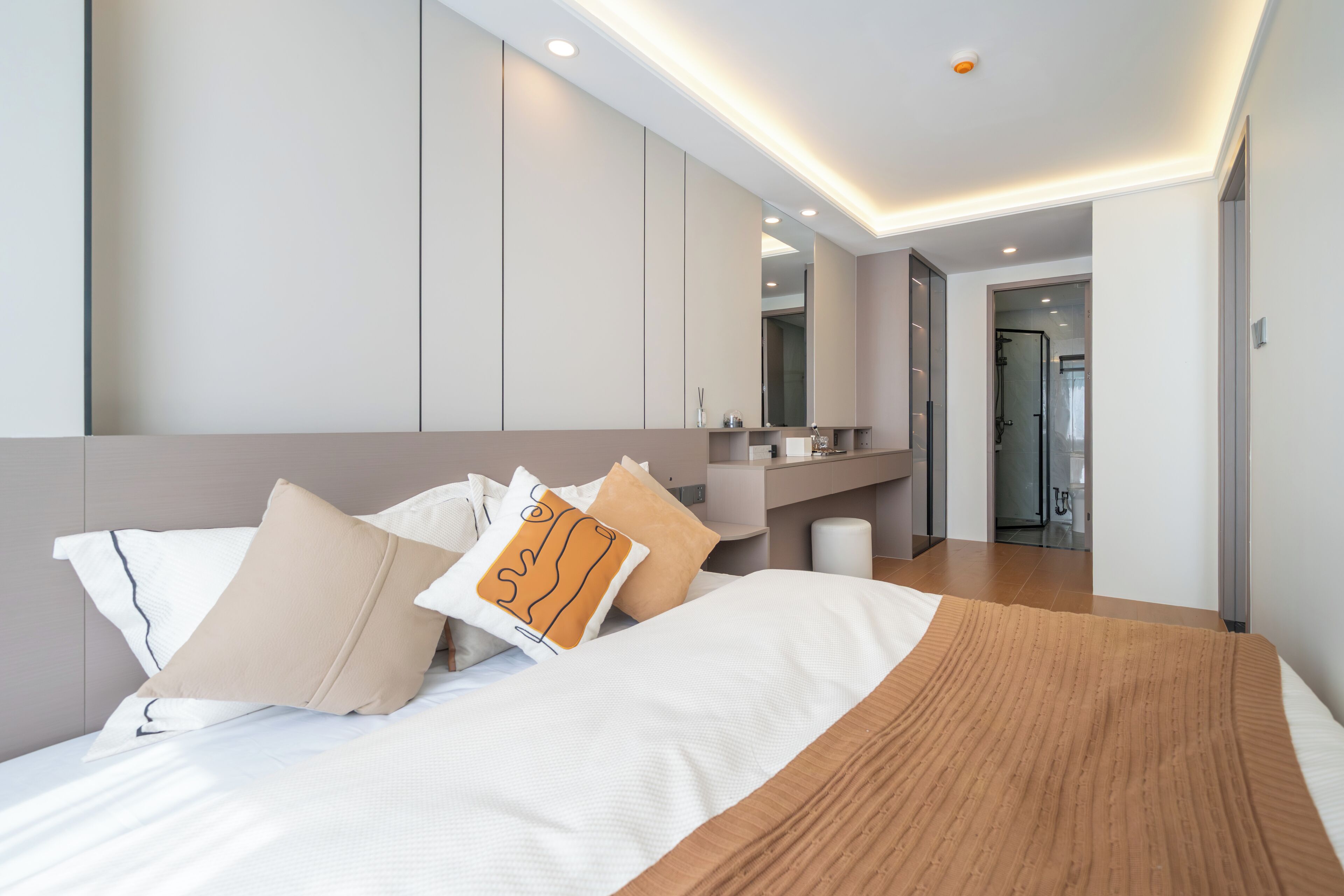 A modern hotel room with a large bed, a bathroom with a shower, and a walk-in closet.