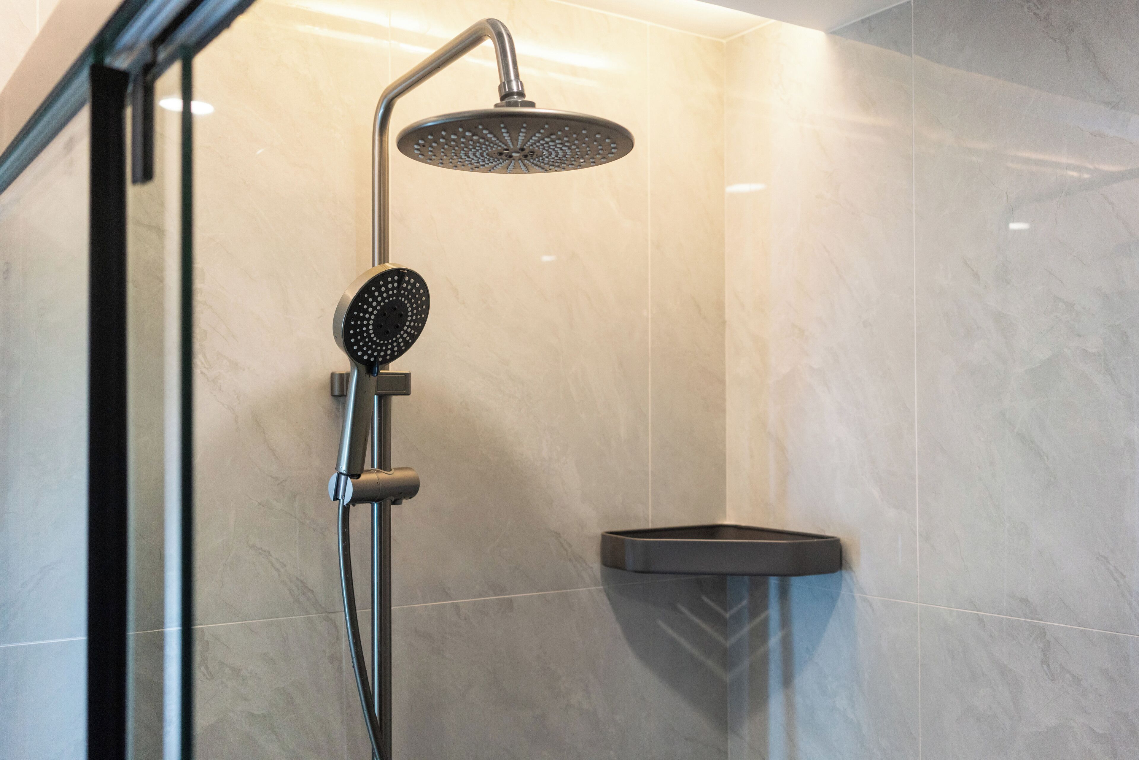 A modern shower with a handheld showerhead and a wall-mounted control panel.