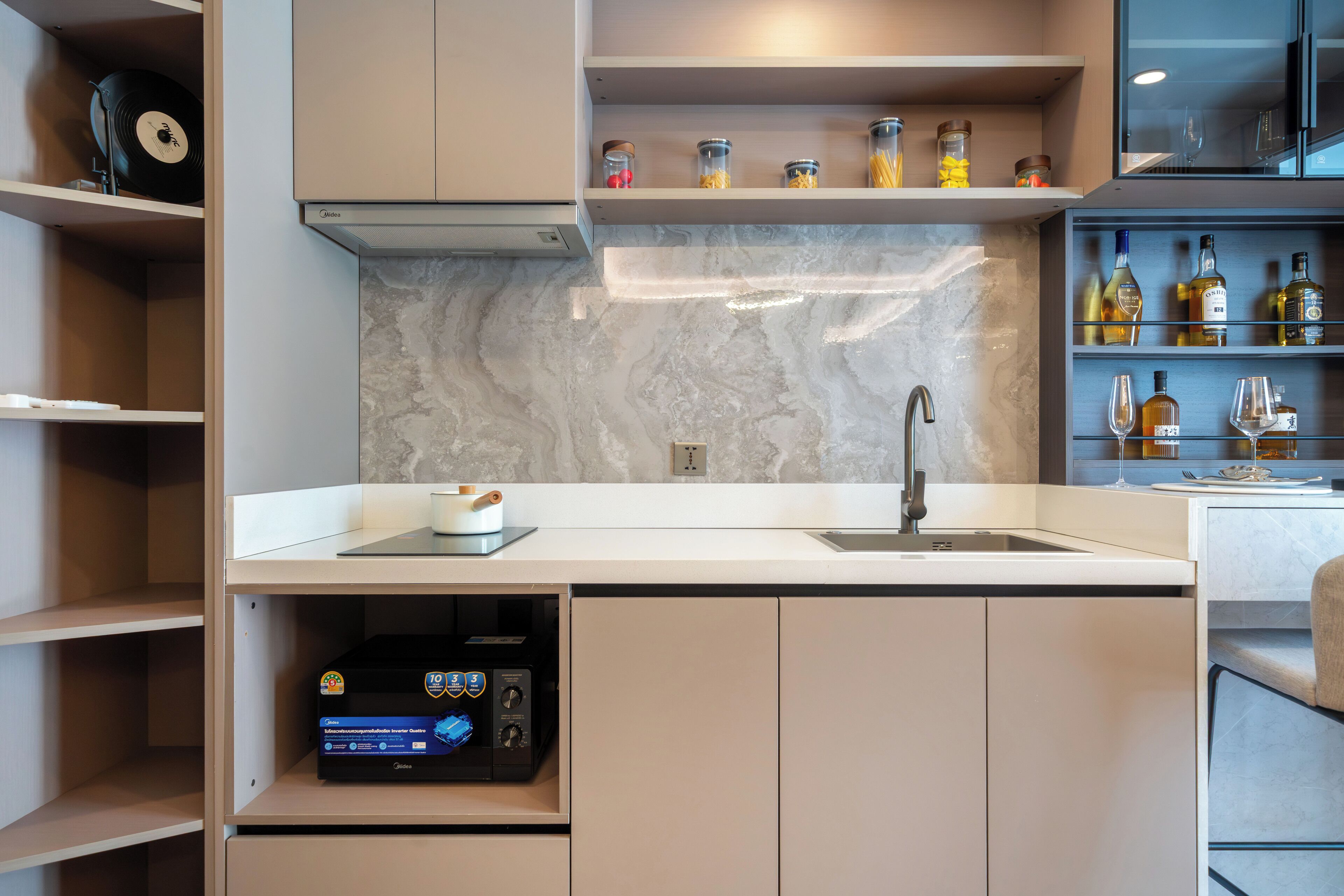 Een moderne keuken met een marmeren spatwand, ingebouwde planken met potten en een wijnrek.