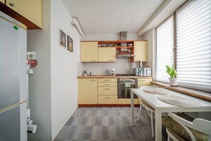 Kompakti keittiö, jossa on ruokailutila, sisäänrakennettu uuni ja ikkuna, jossa on sälekaihtimet.