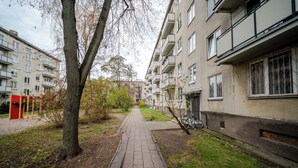 A residential pathway flanked by apartment buildings, a tree, and a bicycle. - Cosy 2 Bed Flat in Naujamiestis (Luton)