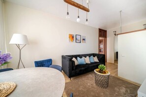 Ein modernes Wohnzimmer mit einer schwarzen Couch, einem runden Tisch und einer Lampe.