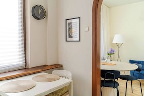Ein Zimmer mit einem Esstisch, Stühlen, einer Uhr und einem gerahmten Bild an der Wand.