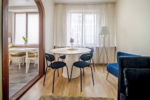 A modern living room with a round table, chairs, a blue sofa, and a floor lamp. - Cosy 2 Bed Flat in Naujamiestis (Luton)