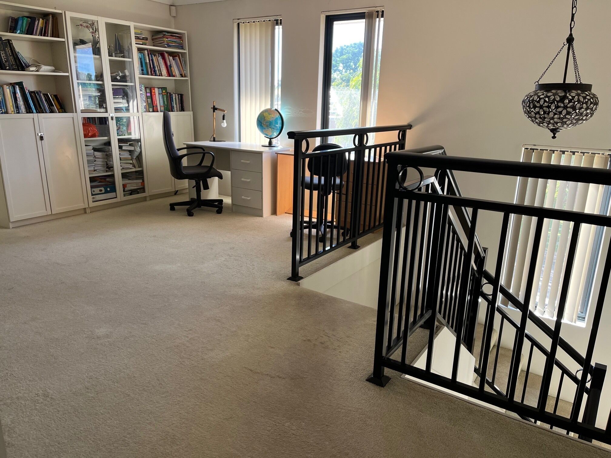 A study room with a desk, two chairs, a globe, and bookshelves.