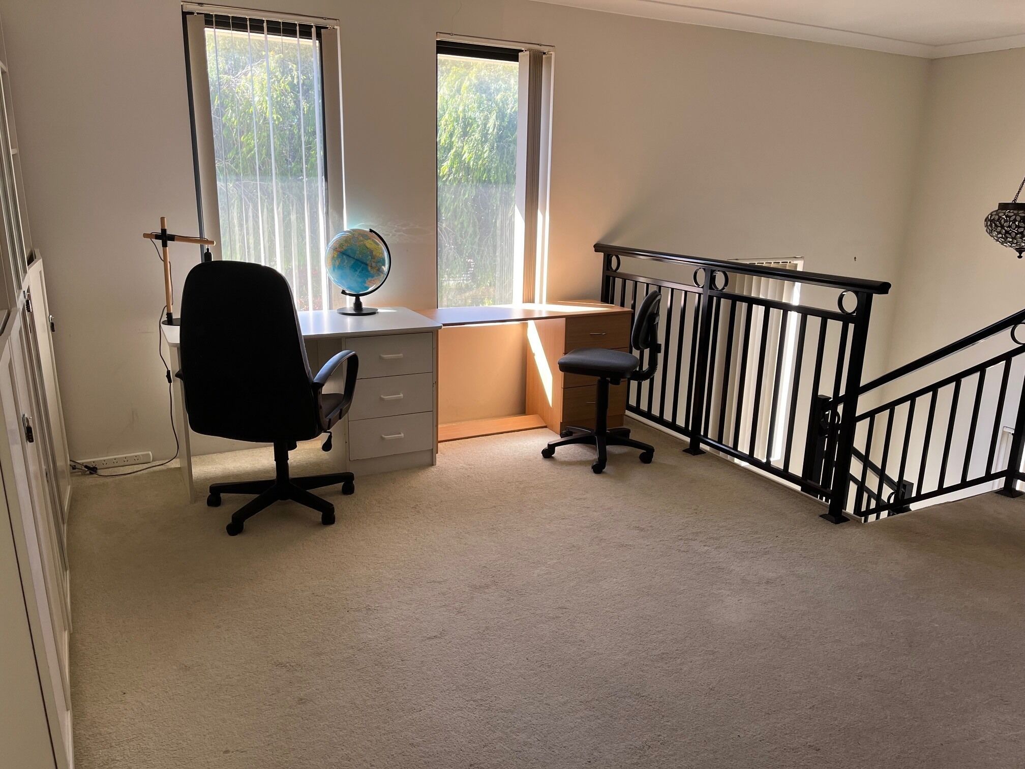 Ein Arbeitszimmer mit Schreibtisch, Stuhl, Globus und einer Treppe mit Geländer.
