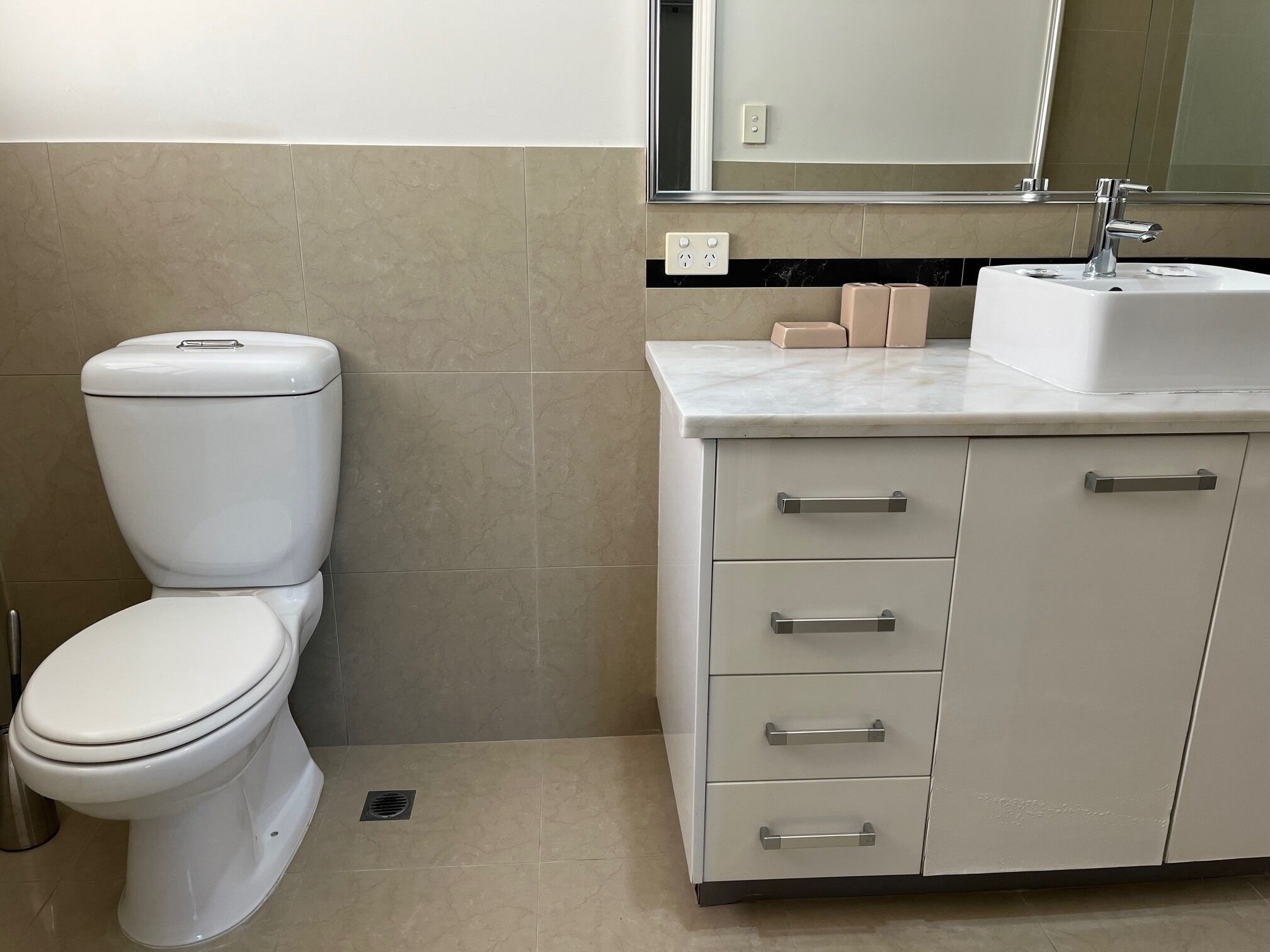 A bathroom with a toilet, sink, and cabinet with drawers.