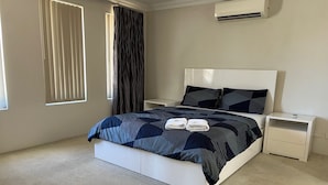 Una camera da letto moderna con un letto grande, un comodino e un condizionatore.