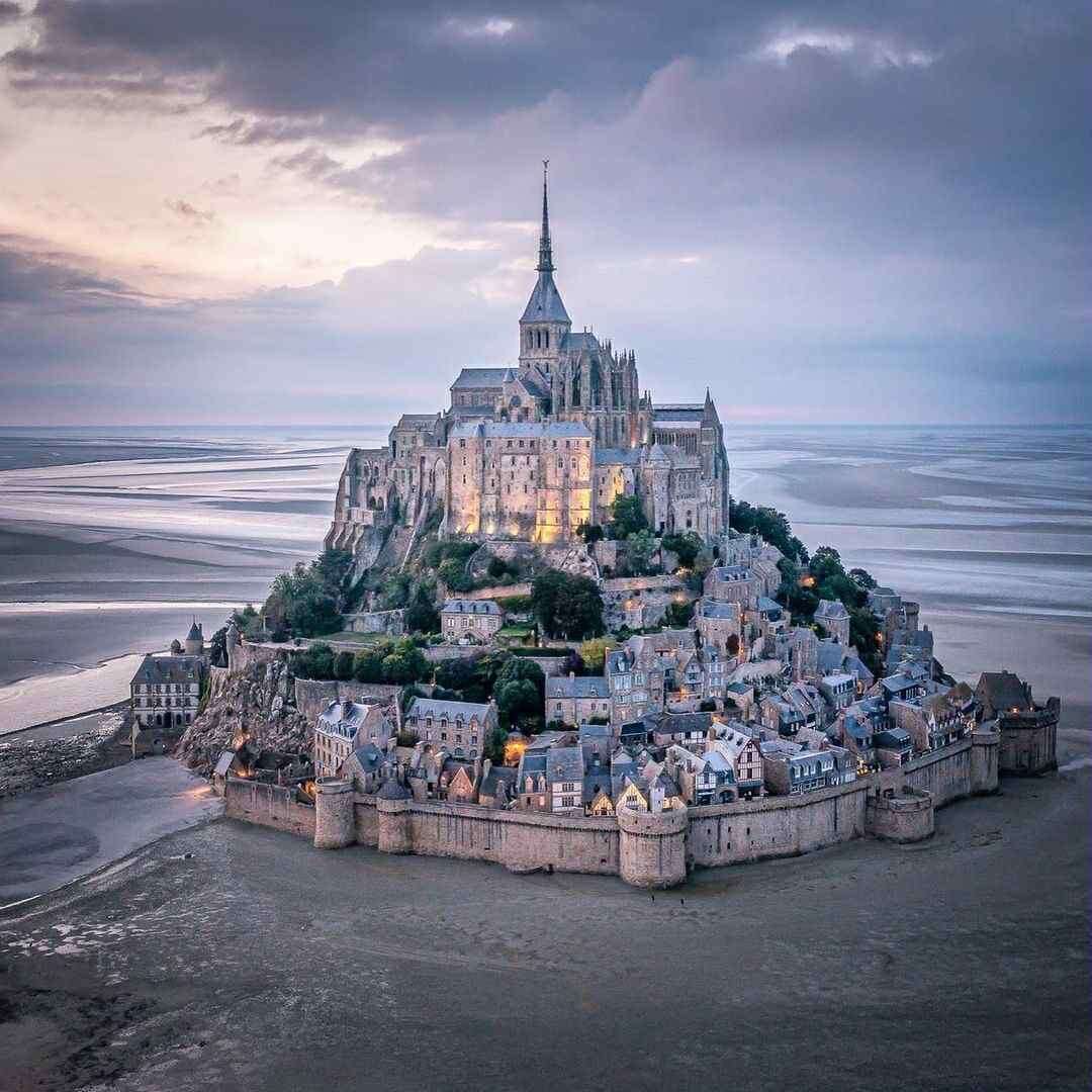 Un château historique, doté d’une tour imposante, situé sur une falaise côtière surplombant une vaste baie.