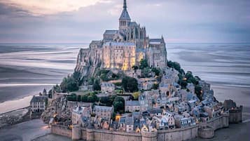 Un château historique, doté d’une tour imposante, situé sur une falaise côtière surplombant une vaste baie.