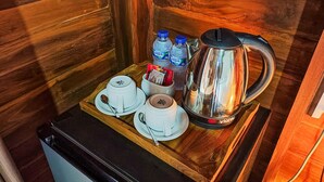 A wooden interior with a tray holding a kettle, two cups, a spoon, and two bottles of water. - Aming Villa Balangan (Jimbaran)