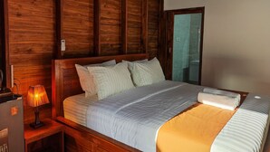 A wooden room with a bed, a nightstand, a lamp, and a bathroom visible through a glass door. - Aming Villa Balangan (Jimbaran)