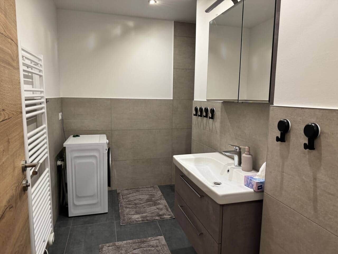 Un baño pequeño con un armario blanco, un lavabo, un espejo y un perchero para toallas.
