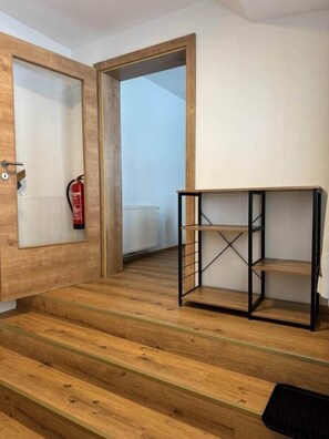 A wooden staircase leading to a room with a black metal shelf unit. - Ski hiking vacation home 92 a Galsterbergblick (Pruggern)