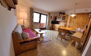 A cozy living room with a sofa, a small table, and a wooden dining table. - Apartment 'Casa Rustica App Bulaccia' with Mountain View, Shared Garden & Balcony (Sankt Ulrich)