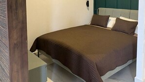 Une chambre à coucher moderne avec un grand lit, une table de chevet et une tête de lit intégrée.