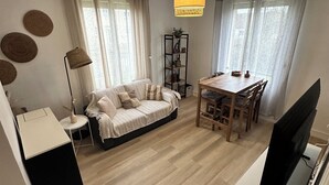 A modern living room with a sofa, dining table, and TV.