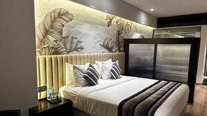 Une chambre moderne avec un grand lit, une tête de lit ornée d’un motif de feuilles, une table de chevet avec une lampe et un plancher en bois.