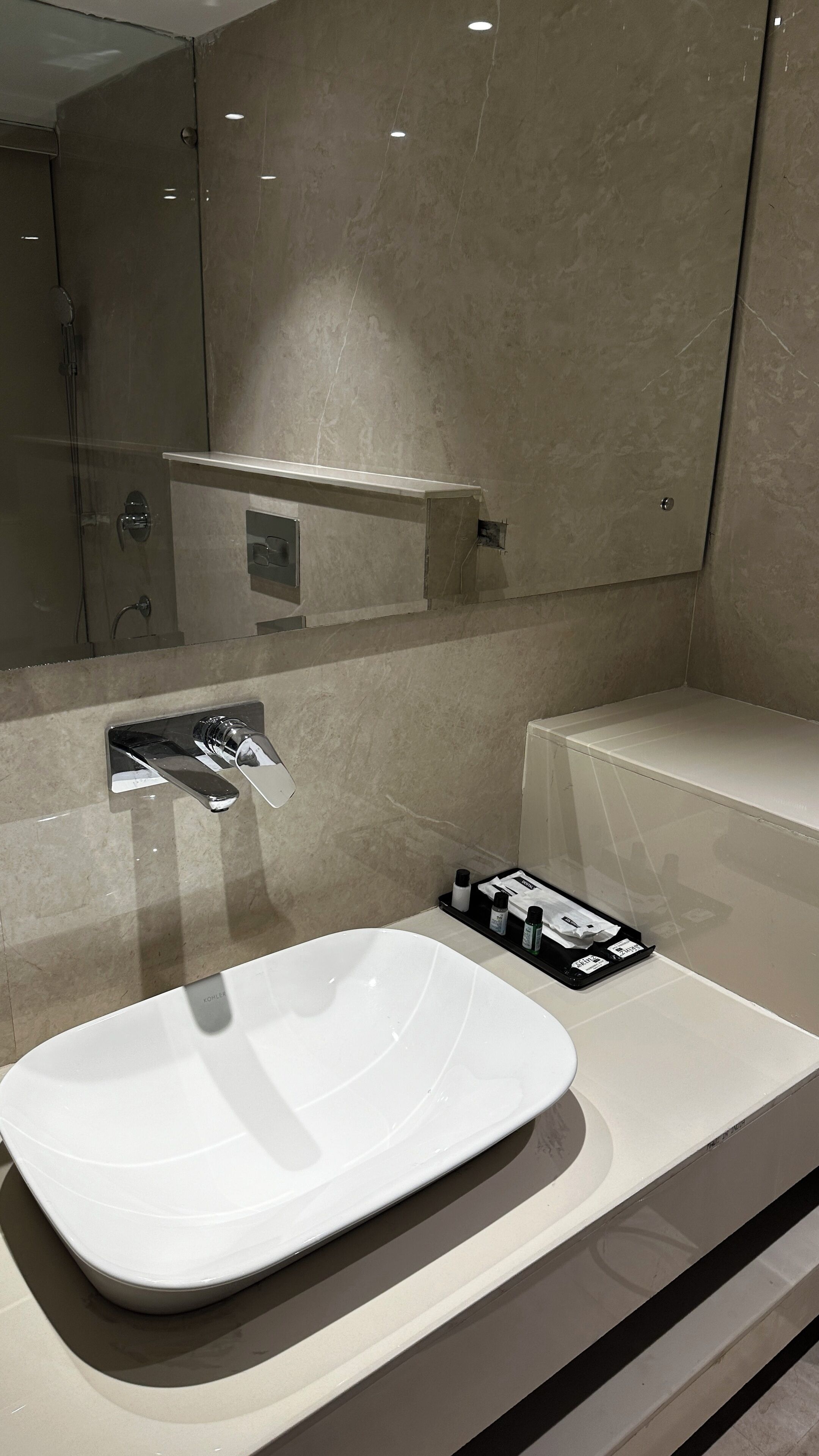 Ein modernes Badezimmer mit einem großen weißen Waschbecken, einem Spiegel und einem Handtuchhalter.