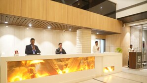 Un comptoir d’accueil avec trois employés, un foyer et un aménagement intérieur moderne.