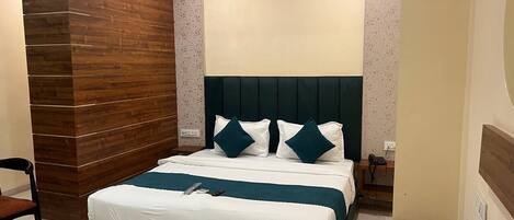 Una habitación de hotel moderna con una cama grande, cabecera oscura y una pared decorativa de madera.