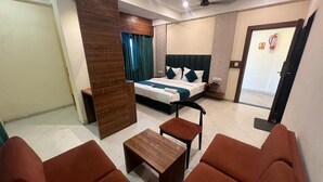 Ein modernes Hotelzimmer mit einem Bett, einer Holzkommode, einem kleinen Tisch und zwei Sofas.
