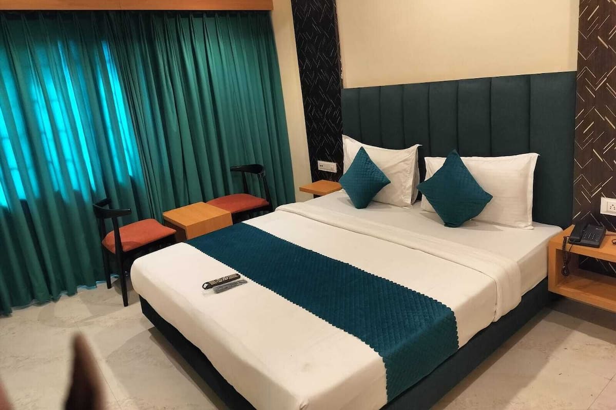 A hotel room with a bed, a desk, a chair, and a telephone.