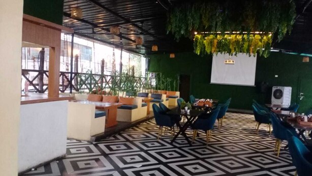 Ein Restaurant mit einem geometrisch gemusterten Boden, grünen Wänden und blauen Stühlen.
