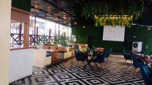 En restaurang med ett golv i geometriskt mönster, gröna väggar och blå stolar.