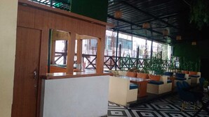 Ein Restaurant mit Holzsitzgelegenheiten und beigen Akzenten, einem gemusterten Boden und einer Aussicht nach draußen durch große Fenster.
