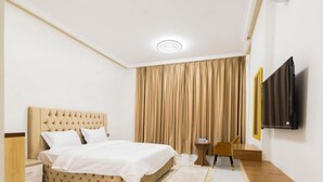 Ein Hotelzimmer mit Bett, Wandfernseher, Schreibtisch und Stuhl.