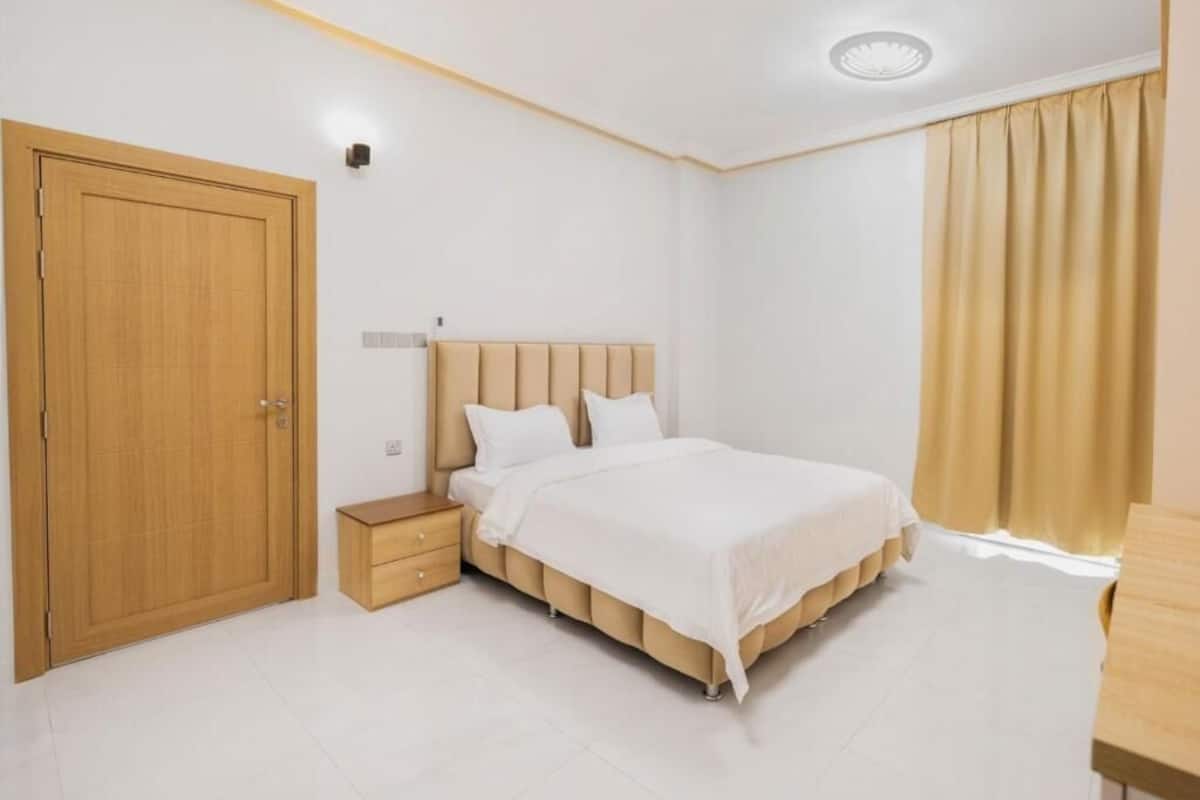 Ein Schlafzimmer mit Bett, Nachttisch, Kleiderschrank und Vorhängen.