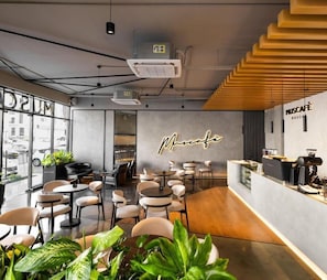 Um café moderno com mesas e cadeiras redondas, balcão de café e uma grande janela com vista para a rua.