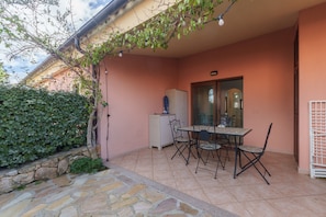 Une terrasse avec une table et des chaises, un chemin en pierre et un meuble blanc.