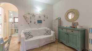 A room with a white sofa, teal cabinet, and wall decorations including a starfish and a sign that says 'Life is Beach.' - Apartment 'Casa Vacanze Gelso' with Shared Pool, Private Garden and Air Conditioning (Murta Maria)