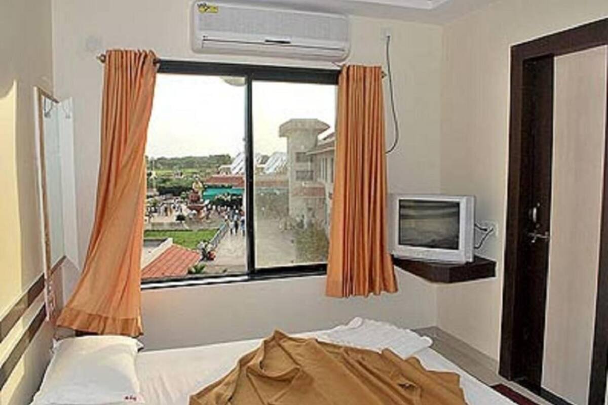 Ein Hotelzimmer mit Bett, Fernseher auf einem Schrank und einem Fenster mit Vorhängen.
