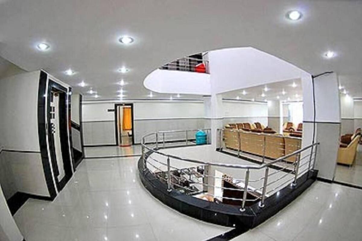 Eine moderne Hotelhalle mit einer zentralen Sitzecke, einer Treppe und einem Empfangsbereich.