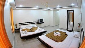A modern hotel room with two beds, a ceiling fan, a flat-screen TV, and a mirror. - KDM Hotel Sai Geeta (Shirdi)