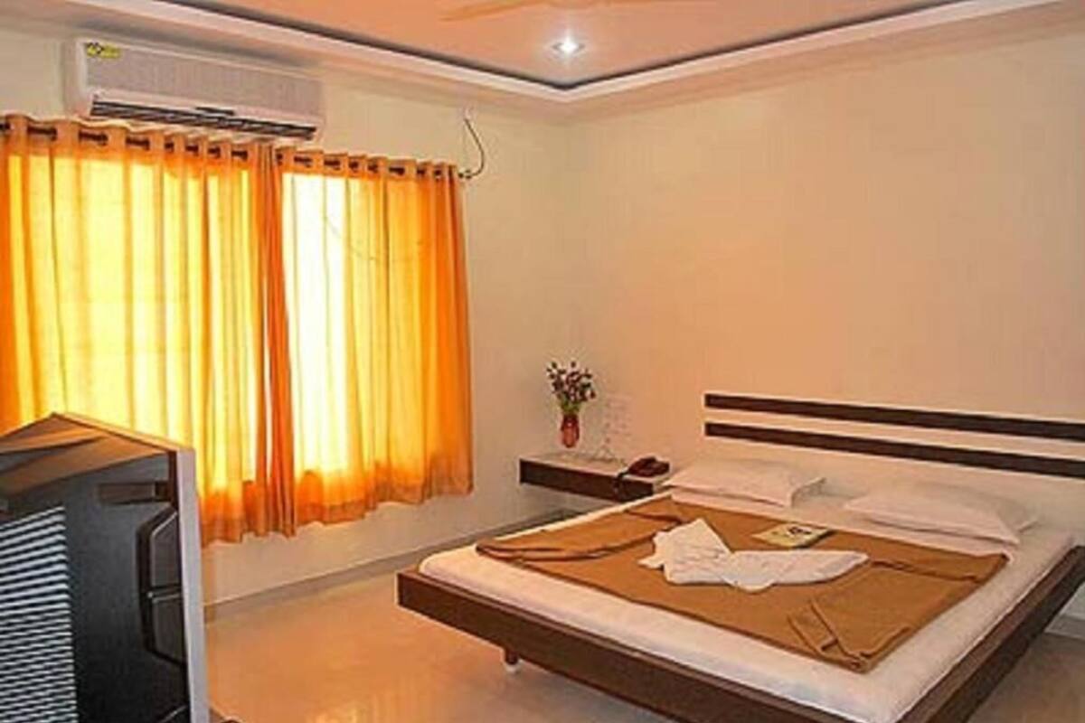 Ein Hotelzimmer mit einem Bett, einem Nachttisch mit Lampe und einer Klimaanlage.