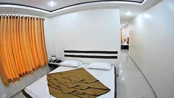 A hotel room with a bed, a nightstand, a mirror, and a window with curtains.