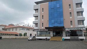 A multi-story hotel with a modern facade, featuring a prominent blue glass section. - KDM Hotel Sai Geeta (Shirdi)