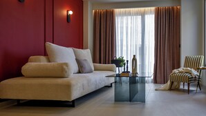 Un soggiorno moderno con un divano color beige, un tavolino in vetro e una poltrona a righe.