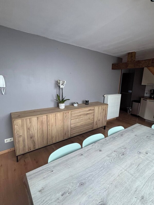 Una cocina moderna con un armario de madera, un radiador blanco y una mesa de comedor con sillas.