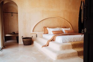 Ein Schlafzimmer mit einem Bett, einem Holzkopfteil, einem Korb und einer Tür.