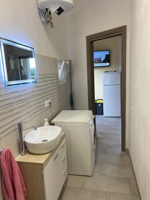 A modern bathroom with a sink, mirror, and washing machine. - RELAX&NATURA (Sicilia)