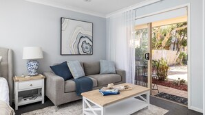 A modern living room with a grey sofa, a wooden coffee table, and a painting on the wall. - Serenity - A place for relaxing (Corlette)