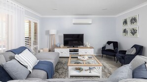 A modern living room with a flat-screen TV, grey sofas, a coffee table, and artwork on the walls. - Serenity - A place for relaxing (Corlette)