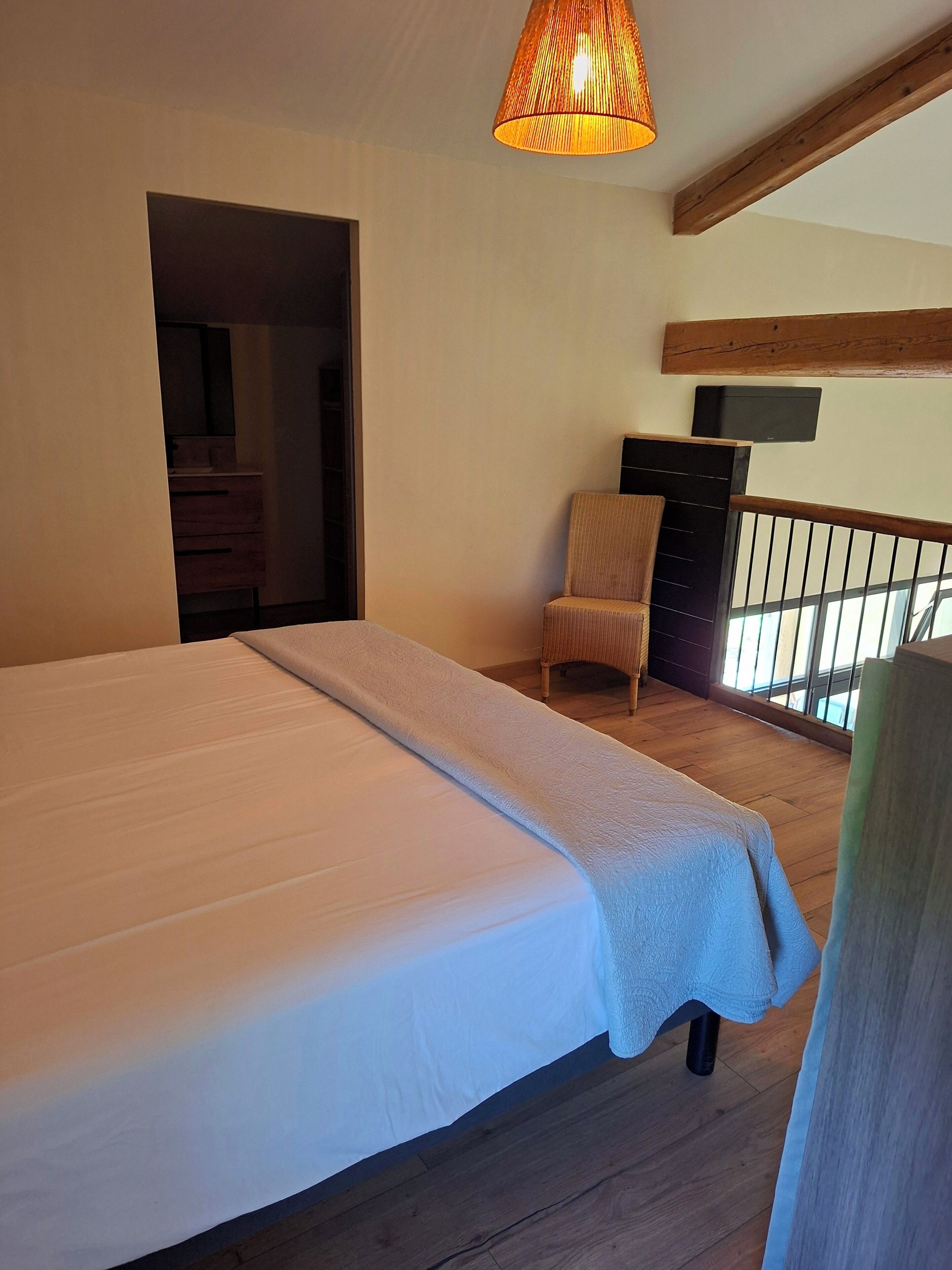 Een slaapkamer met een groot bed, een stoel, een televisie en een houten plafond.