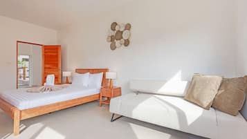 A modern bedroom with a wooden bed, a white sofa, and a decorative wall piece.
