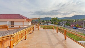 A balcony with a bamboo railing overlooking a residential street and mountains. - Tom Star Pool Villa Layan 3BR Large pool, mountain view for the rooftop (ตำบล ศรีสุนทร)